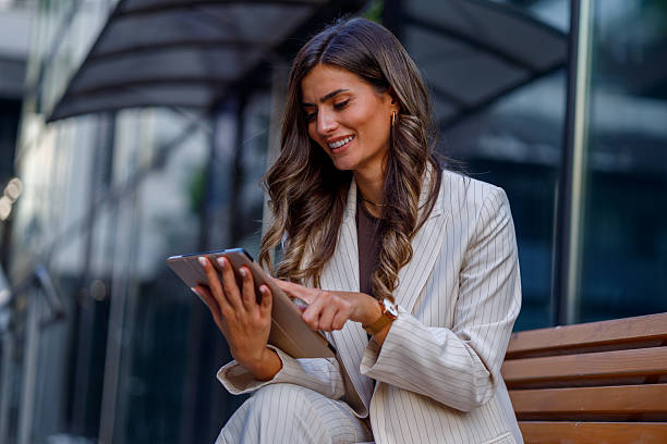 istock Professional woman working on tablet while sitting outdoors, radiating confidence in urban business environment 2235451038