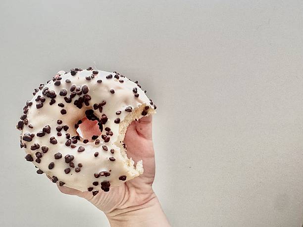 Hand holding bitten donut with icing