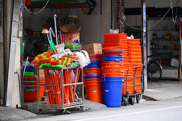 Taiwan - Sep 06, 2025: Hardware store display with brooms, mops and stacked plastic buckets in orange and blue colors, cleaning supplies arranged on cart.