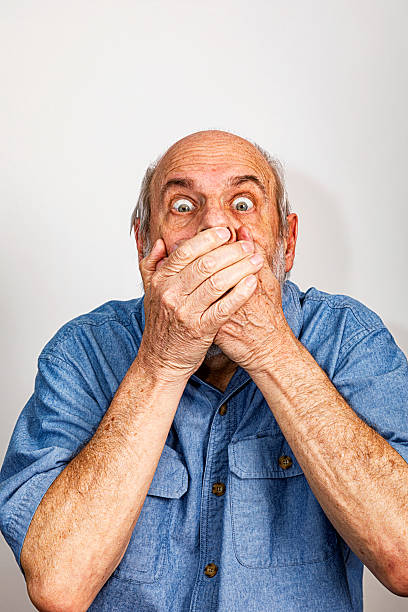 istock Humorous Speak No Evil Senior Man With Hands Covering Mouth 2235453580