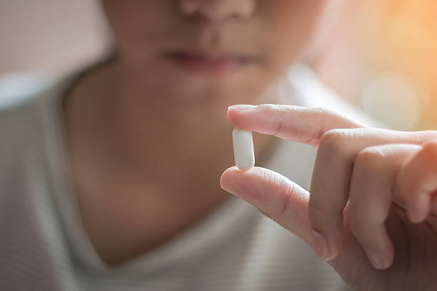 Teenager child girl, Asian youth kid having drug medicine tablet, taking medical pill for pain relief, antibiotic health care medication pharmacy healing from illness or sickness at home stock photo