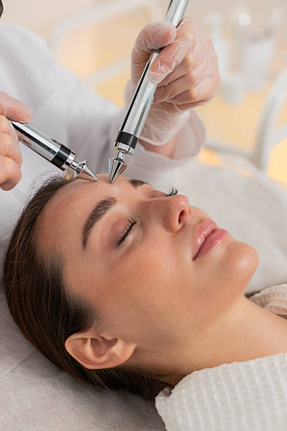 istock Beautician doctor makes woman micro currents face therapy using electrical impulses in spa salon 2235454728