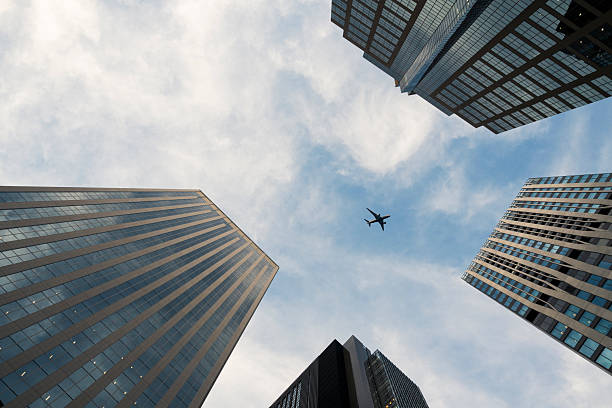 istock Airplane Flying Overhead Between Skyscrapers 2235462856