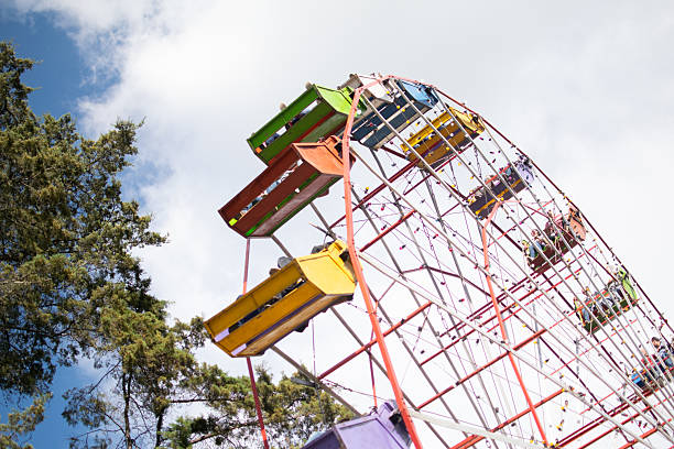 Villach, Austria - July 29, 2025: Brightly colored gondolas of a Ferris wheel against a clear sky, capturing the festive spirit of a local fair with copy space