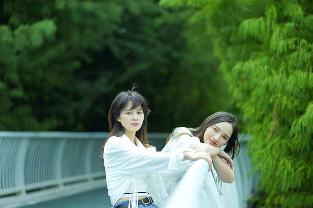 In the lush green outdoors, two girls accompanied each other. They either lean against the railing, with a leisurely posture; Or embrace each other intimately, with a bright smile. The fresh environment blends with sincere friendship, as if every green leaf is witnessing this beautiful moment, showing comfort and warmth.
