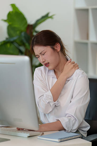 istock Workplace Stress. Young woman experiencing neck pain while working. 2235470671