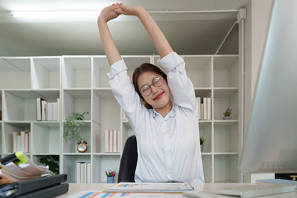 istock Office Stretching. Young woman stretching arms in modern workspace for better health. 2235471397