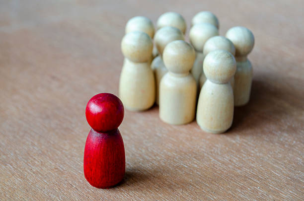 istock A red figurine facing beige figurines illustrating confrontation that may indicate leadership or harassment. 2235473154