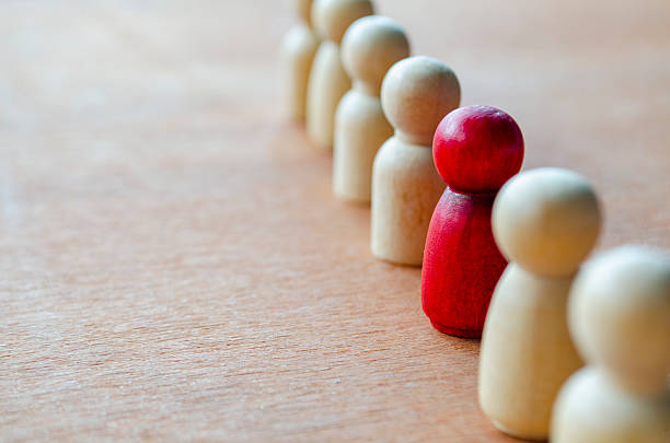 istock A red figurine paired with a beige figurine while others watch representing alignment that may indicate leadership or harassment. 2235473172