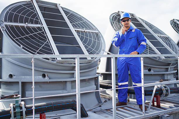 Engineers inspect rooftop HVAC system of high-rise building.