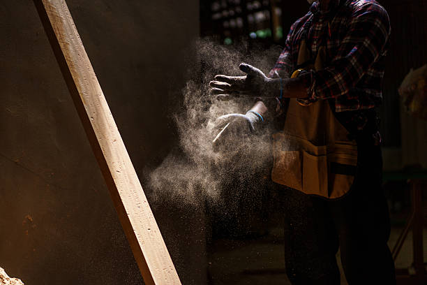 Unrecognizable carpenter brushes sawdust off his hands