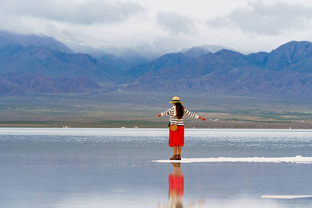 istock Person stands on reflective surface in big landscape, moving forward with hope for future. mountains in background create serene atmosphere 2235484934