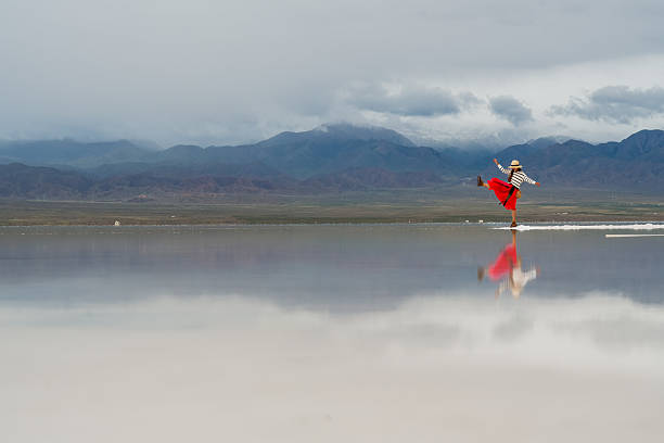 In big landscape, person is moving forward with hope for future, joyfully dancing on reflective surface, embodying freedom and positivity