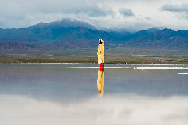 istock Person stands in big landscape, moving forward with hope for future. reflection in water creates serene atmosphere, highlighting beauty of nature and human connection 2235484970