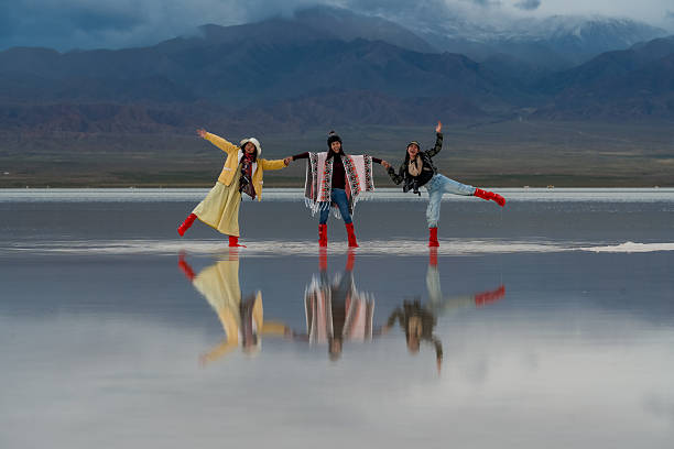 istock Three people wearing colorful outfits and red boots joyfully pose on reflective surface with mountains in background, embodying hope for future as they move forward in big landscape 2235485041
