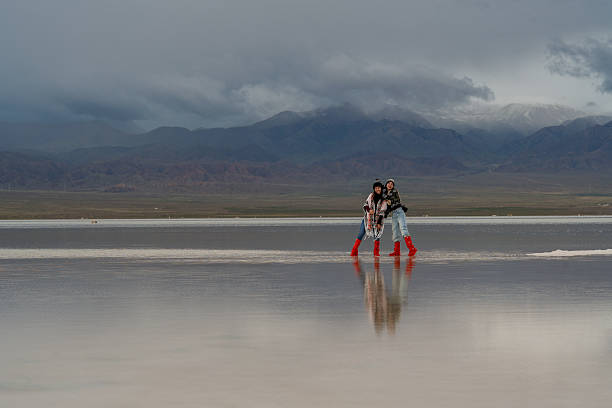 istock Two people are moving forward across big landscape, reflecting hope for future in shimmering water. mountains loom in background under dramatic sky 2235485050