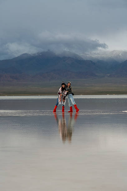 istock Two people wearing red boots stand on big landscape reflecting sky and mountains, moving forward with hope for future in their hearts 2235485053