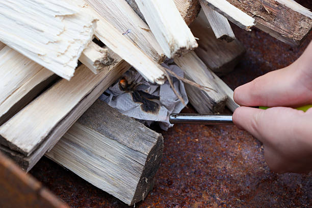 istock A hand lights paper under stacked firewood in a rusty brazier, preparing a bonfire. A close-up shot shows the process of starting a fire. 2235487955
