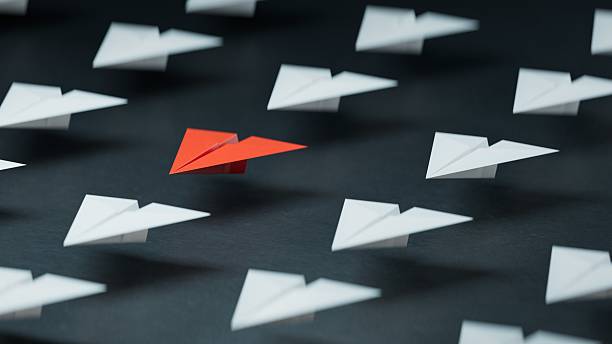 istock Different business concept.new ideas. paper art style. creative idea. red leader plane, standing out from the crowd of white planes.3D rendering on black background. 2235494789