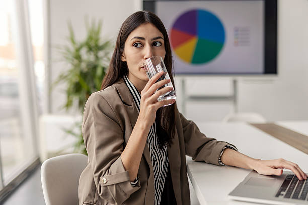 istock Professional Woman Drinking Water While Working in a Modern Office with Graph Display 2235499979