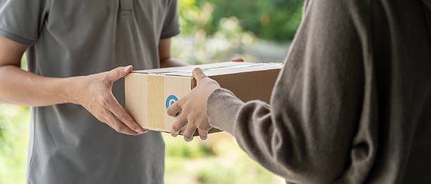 istock Happy smiling woman receives boxes parcel from courier in front house. Delivery man send deliver express. online shopping, paper containers, takeaway, postman, delivery service, packages 2235501890