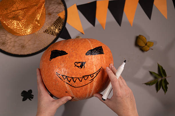 istock Drawing a Jack O'lantern Face on a Pumpkin for Halloween at Home 2235502364