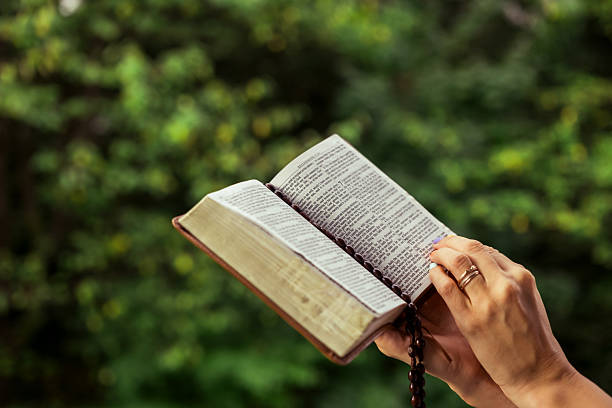 istock Hands holding open Bible with rosary outdoors 2235502964