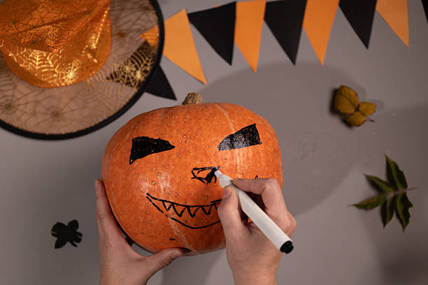 istock Drawing Scary Face on Pumpkin for Halloween Decoration at Home 2235503654