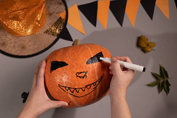 istock Drawing Scary Face on Pumpkin for Halloween Decoration at Home 2235503703