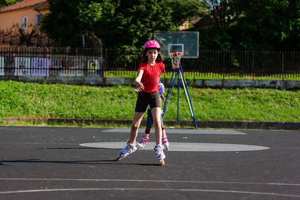Young girl roller skating in a playground on a sunny day