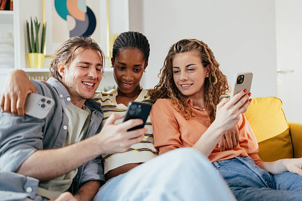 istock Group of young friends using smartphones at home 2235505137
