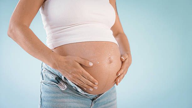 istock Pregnant Woman Applying Lotion on Belly 2235505589