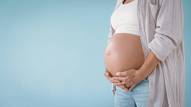 istock Pregnant Woman in Studio Touching Belly 2235505750