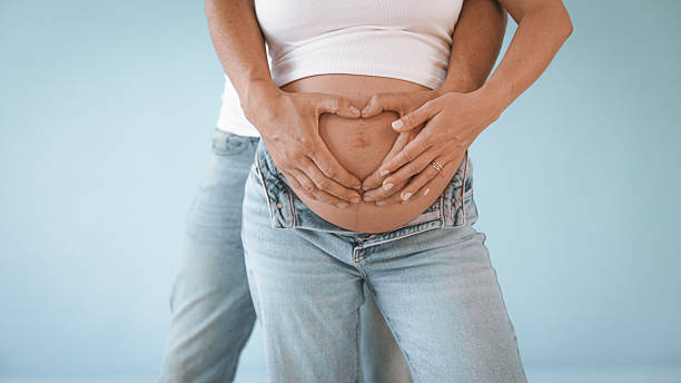 istock Couple Making Heart on Pregnant Belly 2235505973