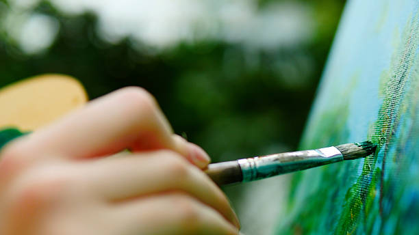 istock Artistic Expression A Hand Holding a Brush on Canvas Surrounded by Natures Beauty 2235506142