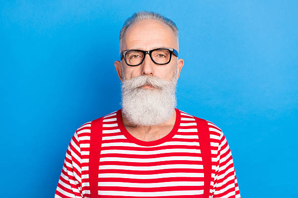 istock Portrait of attractive serious intellectual grey-haired man wearing striped pullover isolated over bright blue color background 2235507287