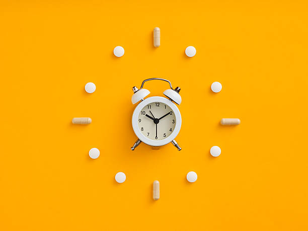 istock White alarm clock and pills forming a clock face on orange background 2235508695