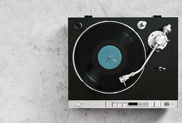 Top view of a vintage turntable playing a vinyl record with a light blue label, placed on a gray background