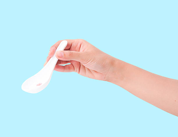 istock Clean white ceramic Asian spoon held by hand on a bright blue background. 2235509112