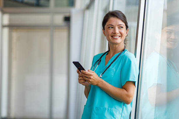 istock Smiling nurse using mobile phone in hospital corridor 2235511012