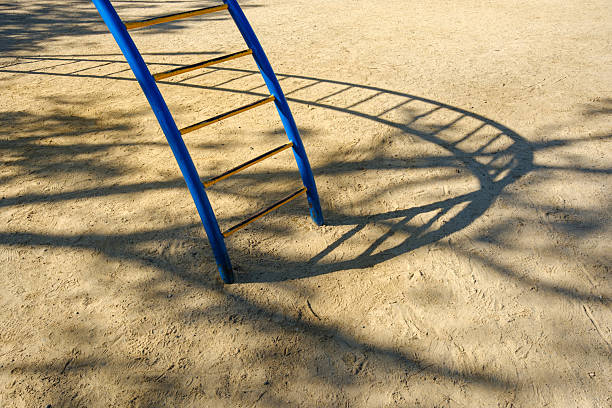 Blue and yellow ladder casting a shadow on the sand.