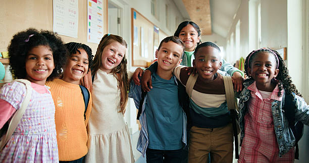 istock Portrait, group and happy children hug for education, teamwork or smile in elementary school. Friends, kids and students embrace for support with development, learning or laugh in hallway together 2235513719