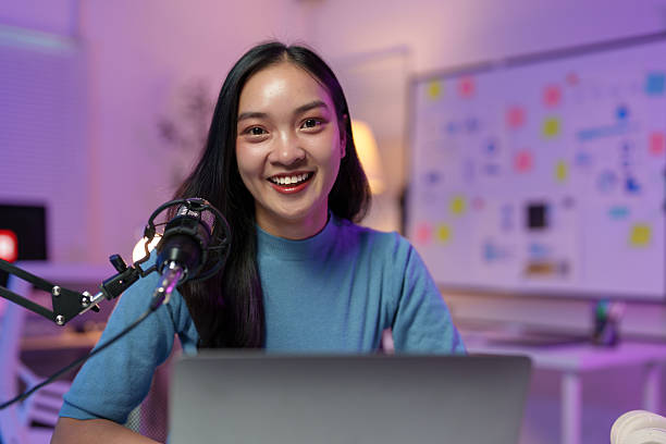 istock Young asian content creator recording a podcast in her home studio, using a professional microphone and laptop, exuding confidence and creativity while engaging with her audience 2235513838