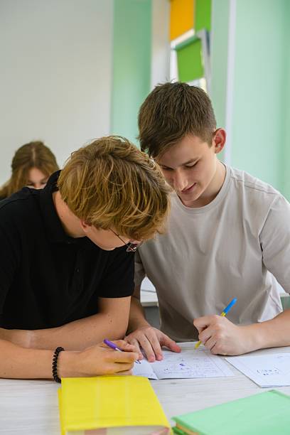 istock High school boys studying together in bright classroom. 2235517538