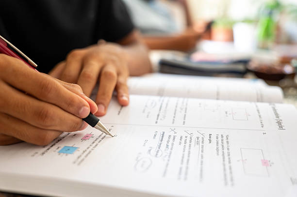 istock Student taking test and filling out answers in exercise book 2235520081