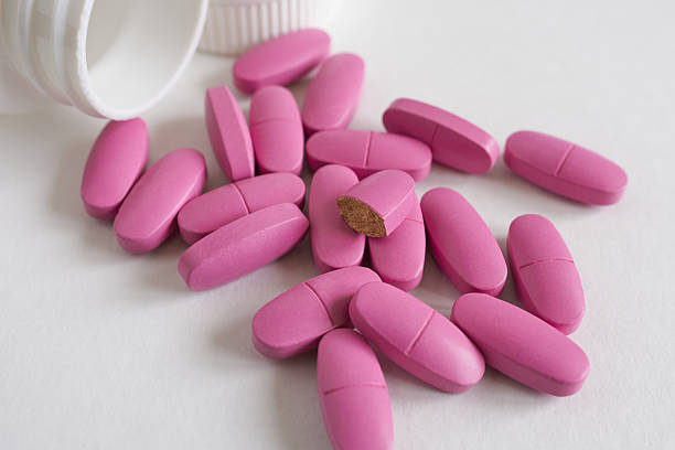 istock pink pills and bottle on a white background close-up. 2235522451