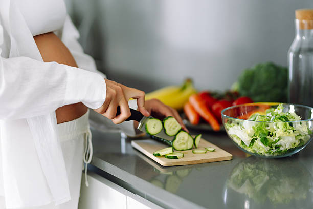 istock A young pregnant woman chops celery while standing in a modern kitchen. 2235523226