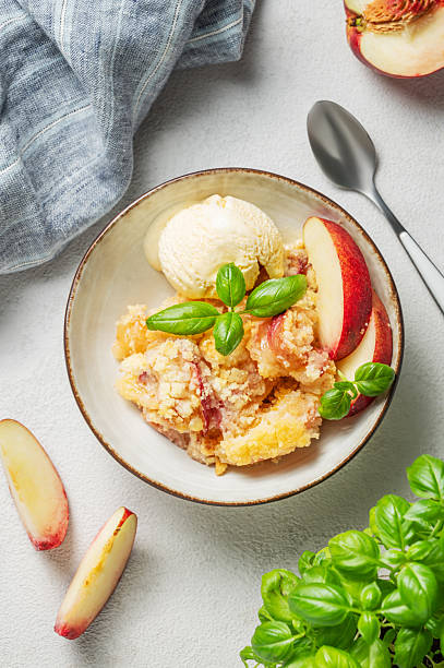 istock Peach crumble or cobbler with vanilla ice cream scoops and cinnamon on a plate on a light background 2235524924