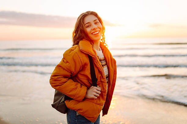istock A beautiful woman with a backpack strolls along the shore at dawn. 2235525323