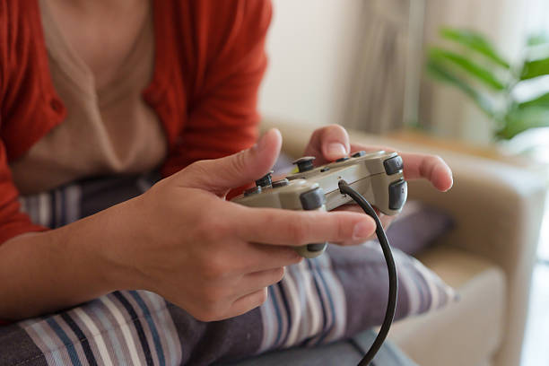 istock Close up of Asian woman holding a console game controller while playing on the sofa at home. 2235525723